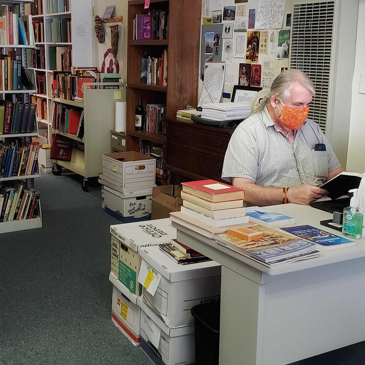 Don Frew, wearing mask, catalogs books at the Adocentyn Research Library
